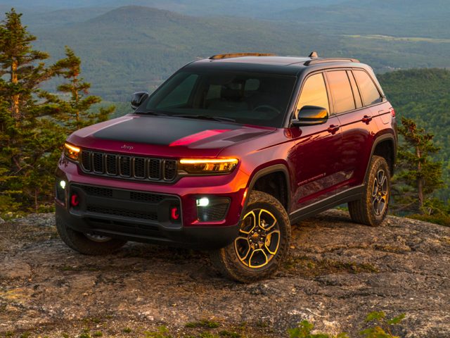 A red 2023 Jeep Grand Cherokee in front of a mountain range.